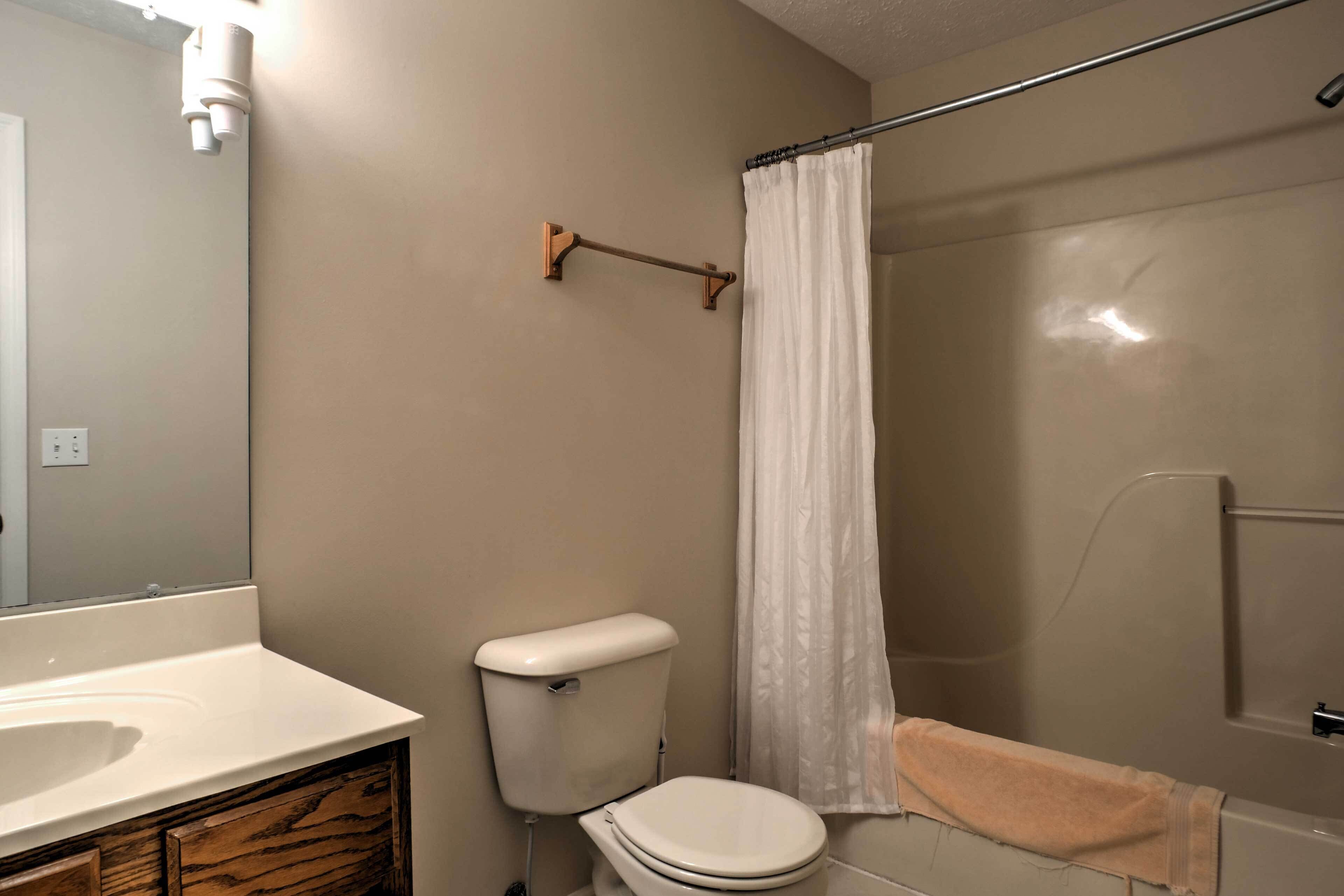 A bathroom with a white sink, toilet, and shower curtain.