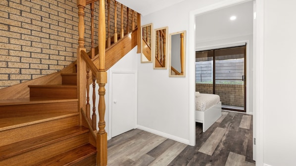 A staircase with wooden balusters leading to a room with a brick wall and a large window.