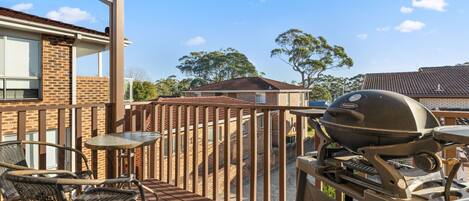 Une terrasse extérieure avec un barbecue, une table et des chaises.