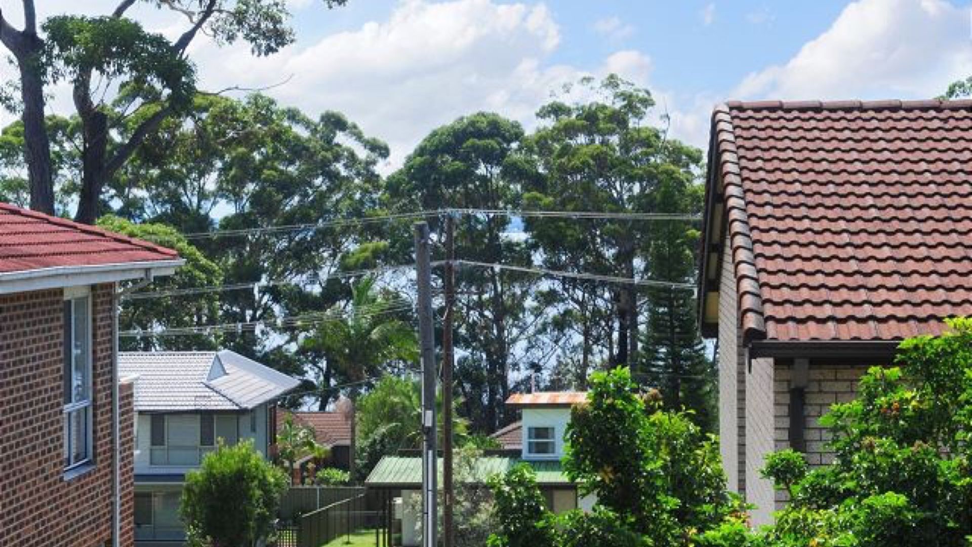A residential area with houses, a clear sky, and trees.