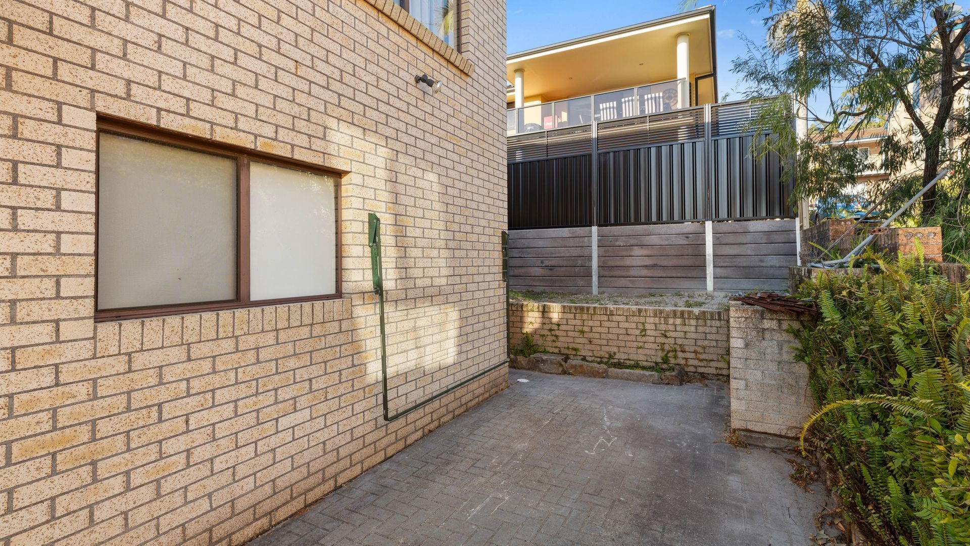 A narrow brick alleyway with a window and a metal gate.