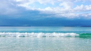 A beach with waves and a clear sky.