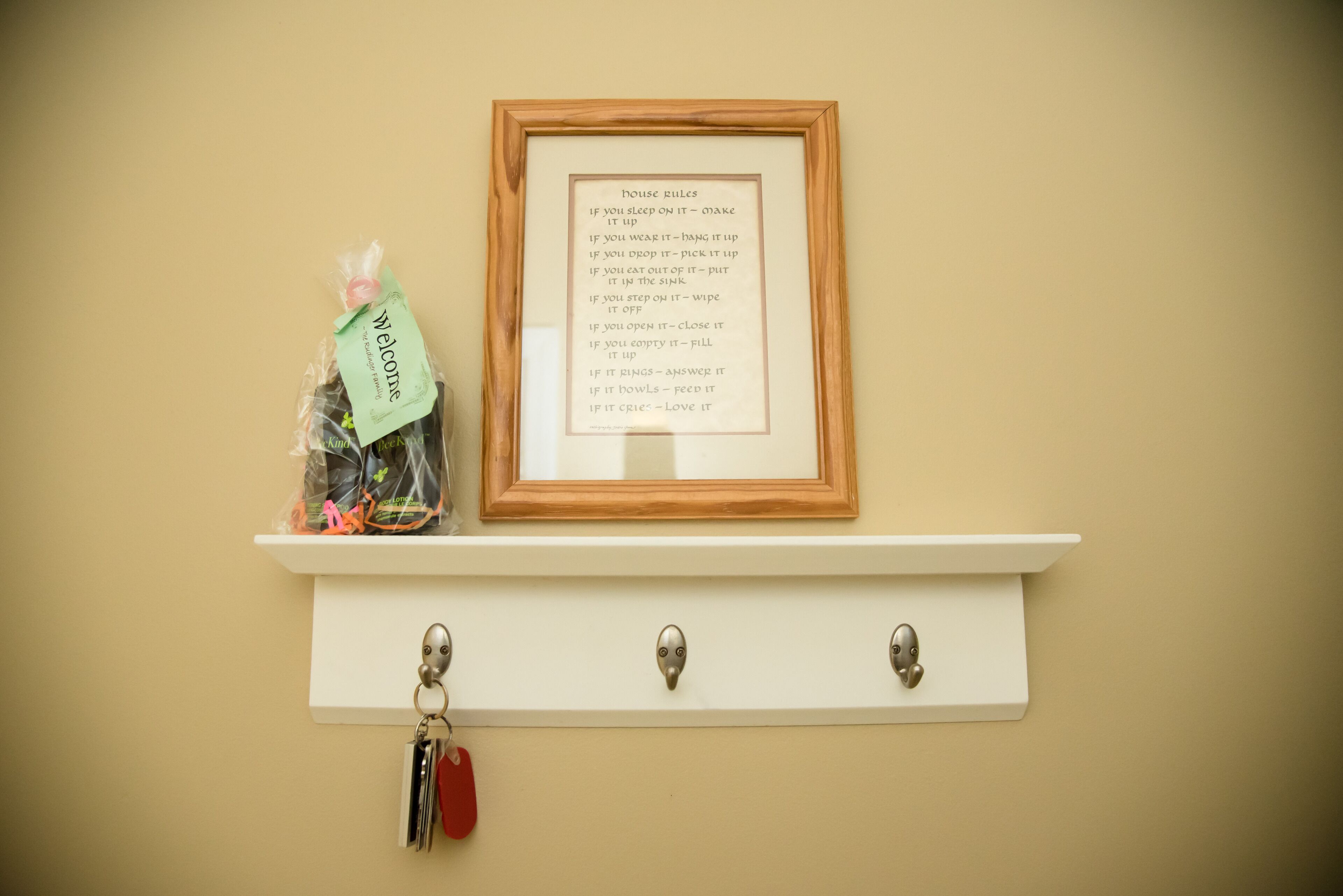 Un ensemble de règles de la maison encadré, accroché au mur, un sac de bienvenue et un porte-clés.