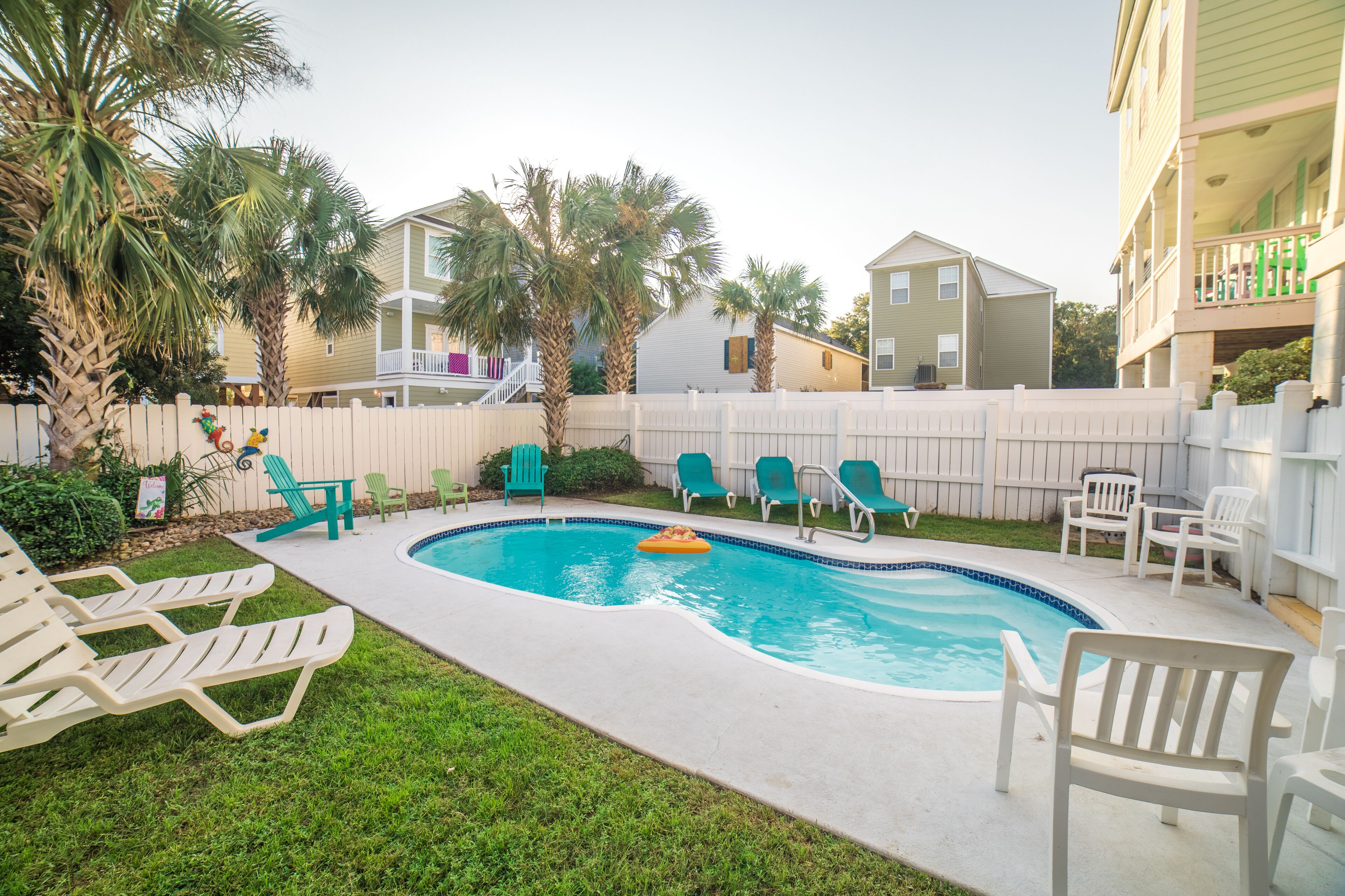 A swimming pool with lounge chairs and palm trees.