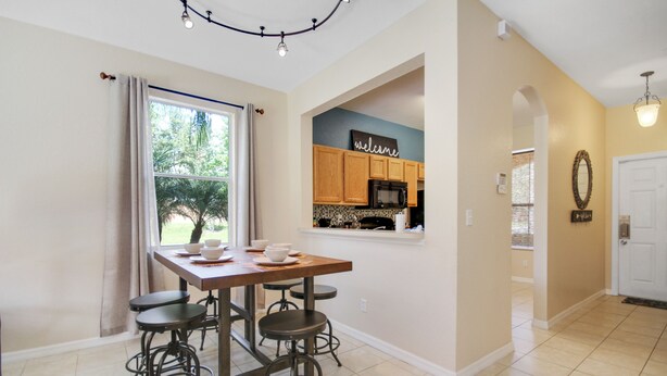 A modern kitchen with wooden cabinets, a microwave, and a 'welcome' sign.