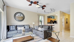 A modern living room with a sofa, coffee table, and a dining area with a glass table.