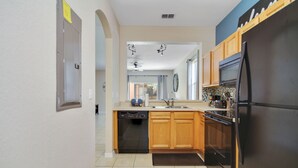 A modern kitchen with wooden cabinets, a black refrigerator, and a dishwasher.