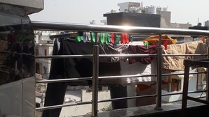 A view of a building with a metal railing and a concrete floor. - Mohit's roof. Residential Rooftop Apartment (Delhi)