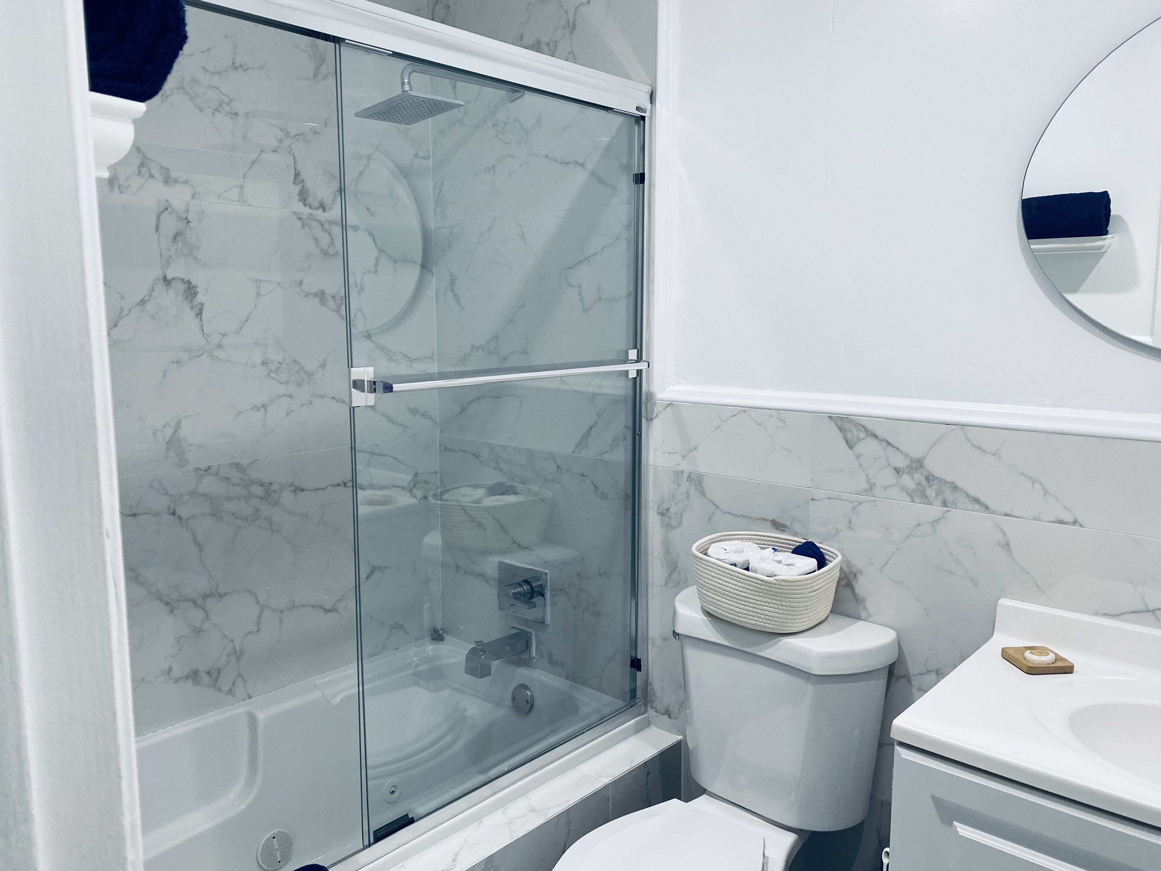 Un baño moderno con ducha envuelta en vidrio, inodoro y lavamanos.