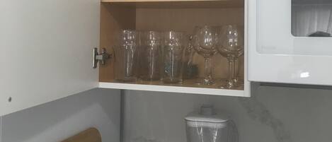 A kitchen with a built-in cabinet containing white dishes, glasses, and a toaster.