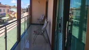 A balcony with a glass door, a chair, and a table. - Casa para 05 pessoas próxima das melhores praias.... (Arraial D'Ajuda (Porto Seguro))