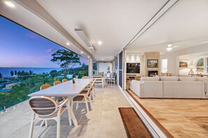 Een moderne woonkamer met een grote televisie, een bank en een eethoek met stoelen en een tafel.