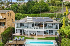 Een tweelaags huis met een balkon, zonnepanelen, een zwembad en een tuin.