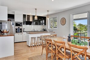 Una cocina moderna con armarios blancos, una mesa de comedor de madera y un amplio ventanal.