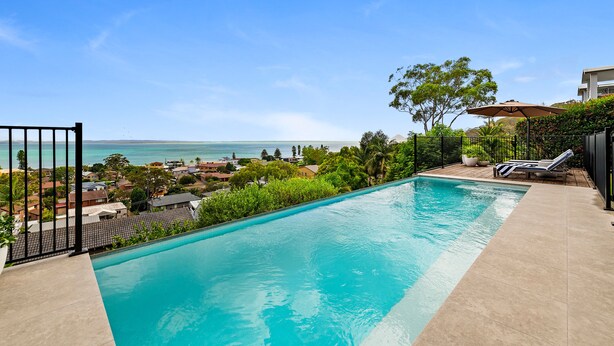 A swimming pool with a view of the sea, surrounded by greenery and a fence. - Phuza Maningi Corlette Home with Private Pool (Corlette)