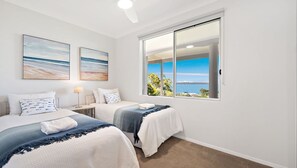 A bedroom with two beds, a large window with a view of the sea, and artwork on the wall. - Spacious, Stylish home with panoramic waterviews (Corlette)