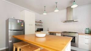 A kitchen with a wooden countertop, a stainless steel refrigerator, a gas stove, and white cabinets. - Solomon Street Cottage (Fremantle)