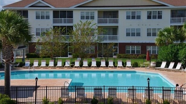 Un hotel con piscina, varios balcones y sillones de descanso.