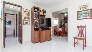 A spacious living area with a wooden entertainment unit, a flat-screen TV, and a dining table with chairs. - Penthouse by Praia do Forte In Cabo Frio (Cabo Frio)