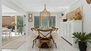A dining area with a white table, wooden chairs, and a hanging light fixture. - Iluka @ Wrights Beach, Jervis Bay (Wrights Beach)