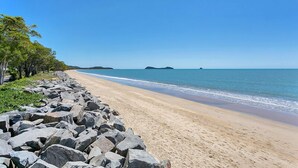 Una playa con costa rocosa y cielo azul despejado.