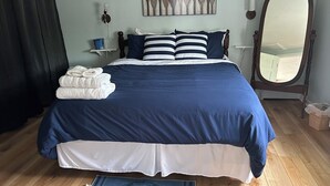 A neatly made bed with a blue and white bedspread, a white throw blanket, and a folded towel on the side. - 1 bed/ba lakeside cottage, large deck, west side of Seneca Lake. Pet Friendly!  (Penn Yan)