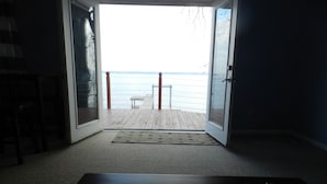An open door leading to a wooden deck with a view of the water. - 1 bed/ba lakeside cottage, large deck, west side of Seneca Lake. Pet Friendly!  (Penn Yan)