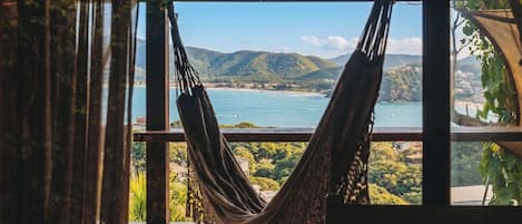 A hammock hanging inside a room with a view of a coastal landscape.
