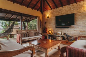 Un espacio de estar acogedor con una pared de piedra, un televisor montado y una hamaca.