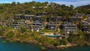 A coastal residential area with multiple two-story buildings, a swimming pool, and dense surrounding vegetation. - Edge 12 Hamilton Island -  absolute oceanfront with golf buggy (Hamilton Island)
