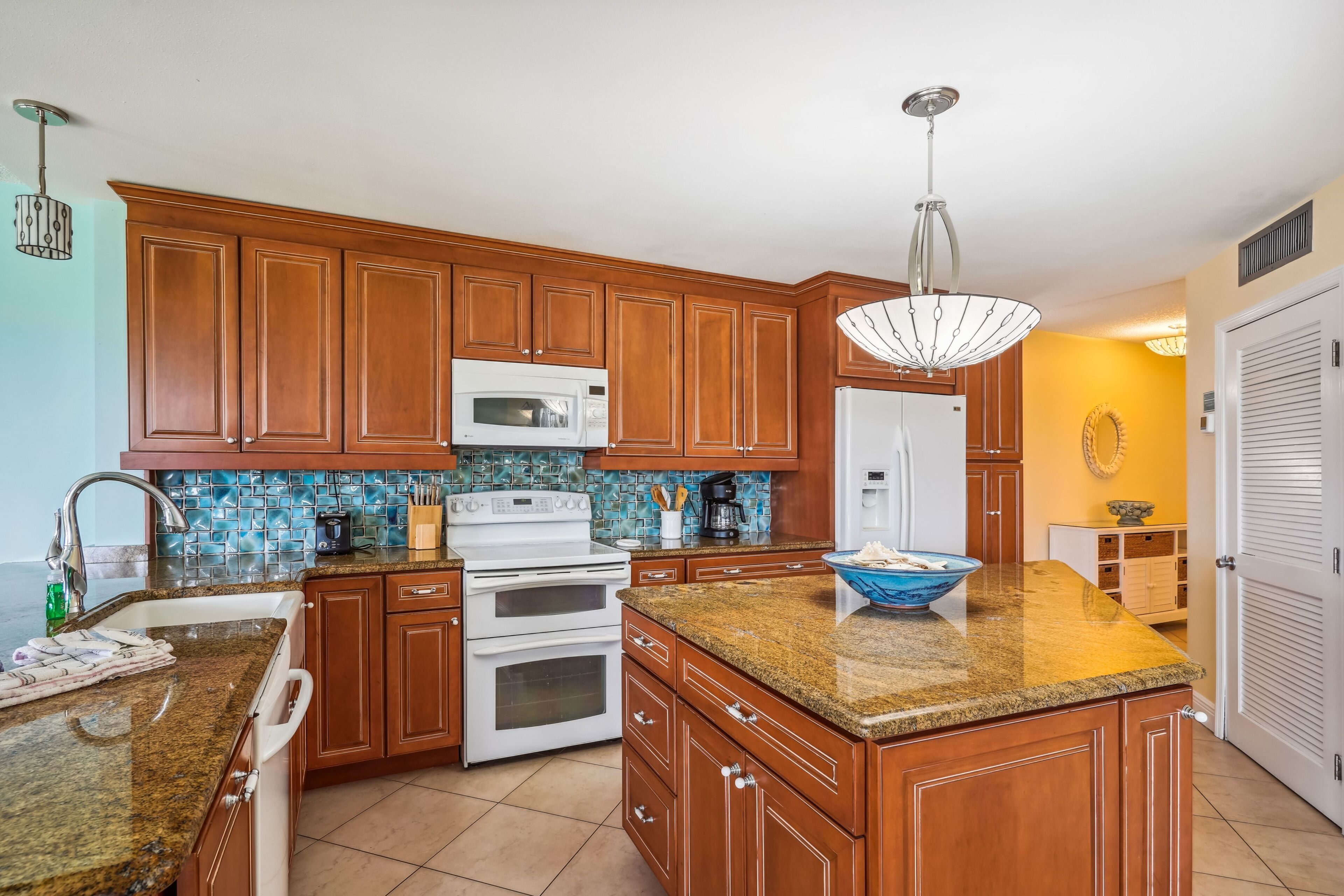 A kitchen with wooden cabinets, a granite countertop, a microwave, a stove, and a sink.