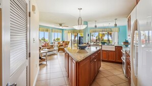 A spacious kitchen with a large island, wooden cabinets, and a modern chandelier.