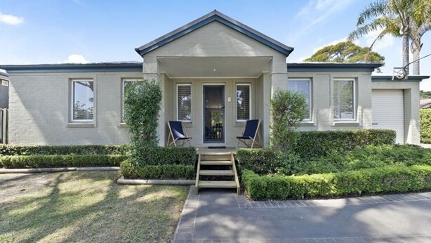 A two-story house with a front porch, a garage, and a well-maintained lawn. - Husky House by Experience Jervis Bay (Huskisson)