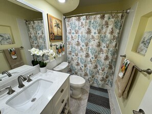 Une salle de bain équipée d’un lavabo, de toilettes et d’un rideau de douche sur le thème de la mer.