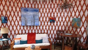 A cozy room with a wooden lattice wall, a sofa with cushions, a small round table, and a chair.