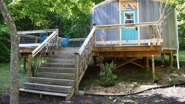 A treehouse with a wooden staircase leading up to a platform with a blue door.