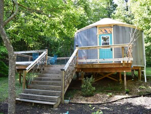 Una casa en el árbol con una escalera de madera que conduce a una plataforma con una puerta azul.