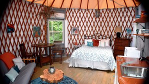A cozy room with a bed, sofa, wooden table, and a small kitchen area.