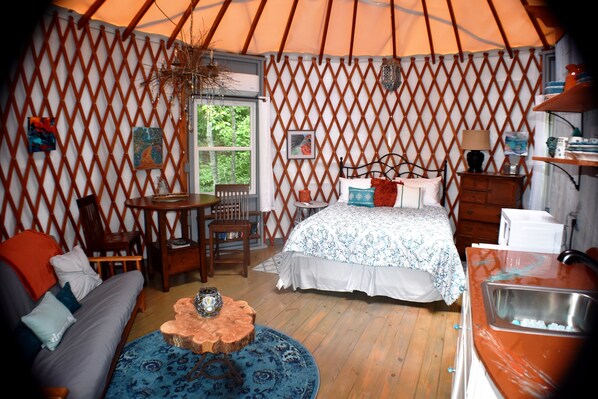 Una habitación acogedora con cama, sofá, mesa de madera y una pequeña cocina.