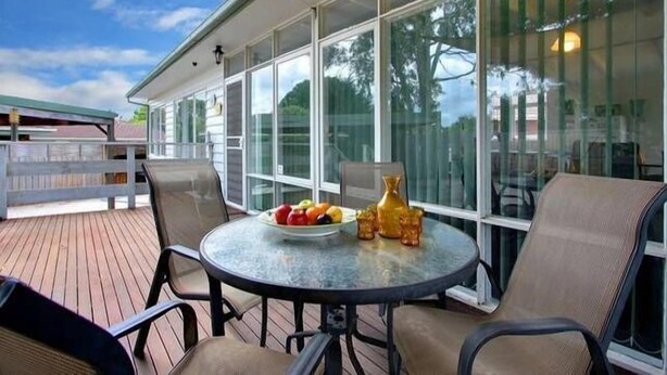 A covered patio with a round table, chairs, and a fruit bowl.
