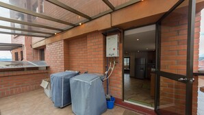 Un espace extérieur abrité, doté d’un mur en briques, d’un barbecue et d’un chauffe-eau.