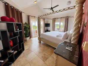 A hotel room with a four-poster bed, a flat-screen TV, a small table with a remote, and a potted plant. - Tropical Villa Ideal for Family Gatherings (Sosua)