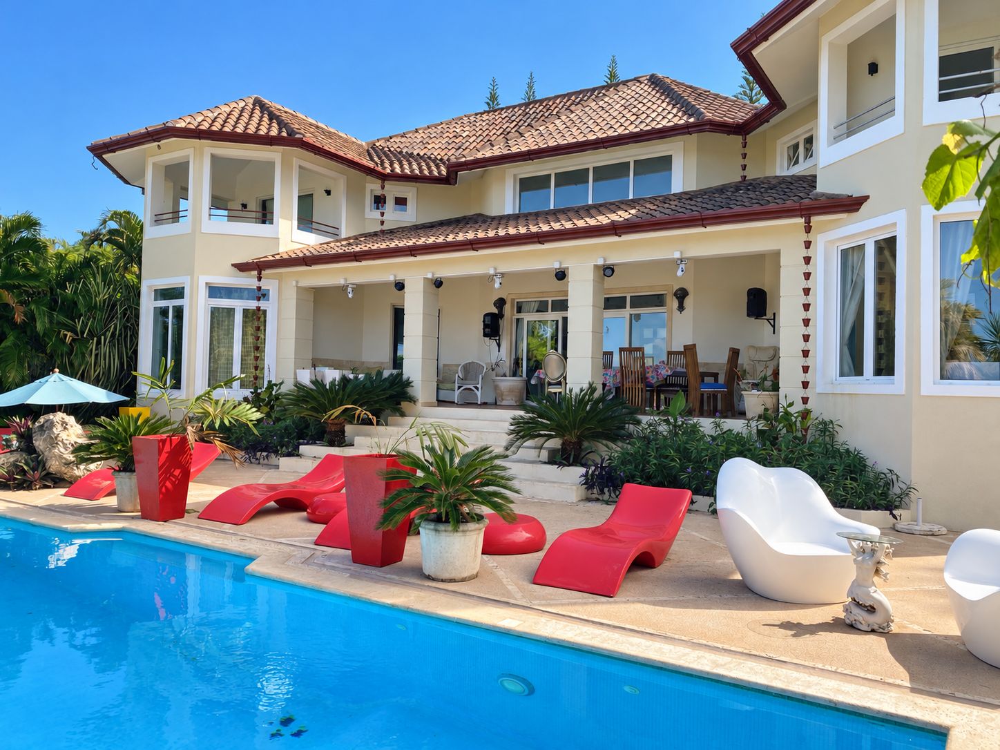 Una casa de dos pisos con piscina, mobiliario exterior y una zona de patio.