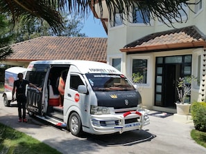 A white van with 'TOURIST TAXI' and 'VIP SERVICE' signage parked in front of a house with a tiled roof. - Tropical Villa Ideal for Family Gatherings (Sosua)