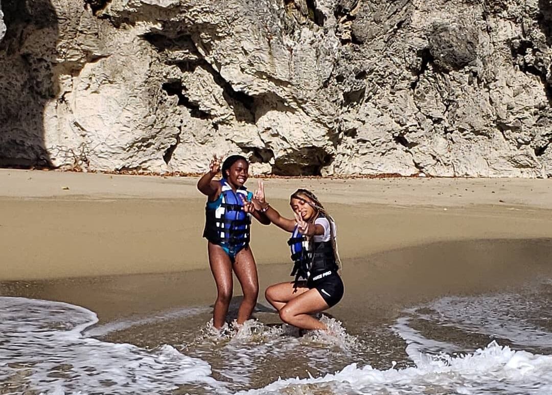 Deux personnes sur une plage rocheuse, avec des vagues en arrière-plan.