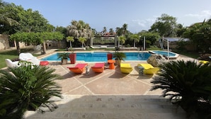 Une piscine avec des chaises longues et des plantes en pot.