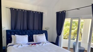 Une chambre à coucher avec un grand lit, du linge de lit blanc et une tête de lit bleue.