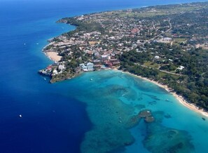 An aerial view of a coastal town with a beach, clear waters, and buildings. - Tropical Villa Ideal for Family Gatherings (Sosua)
