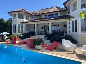 A two-story house with a swimming pool, outdoor seating, and a covered patio area.