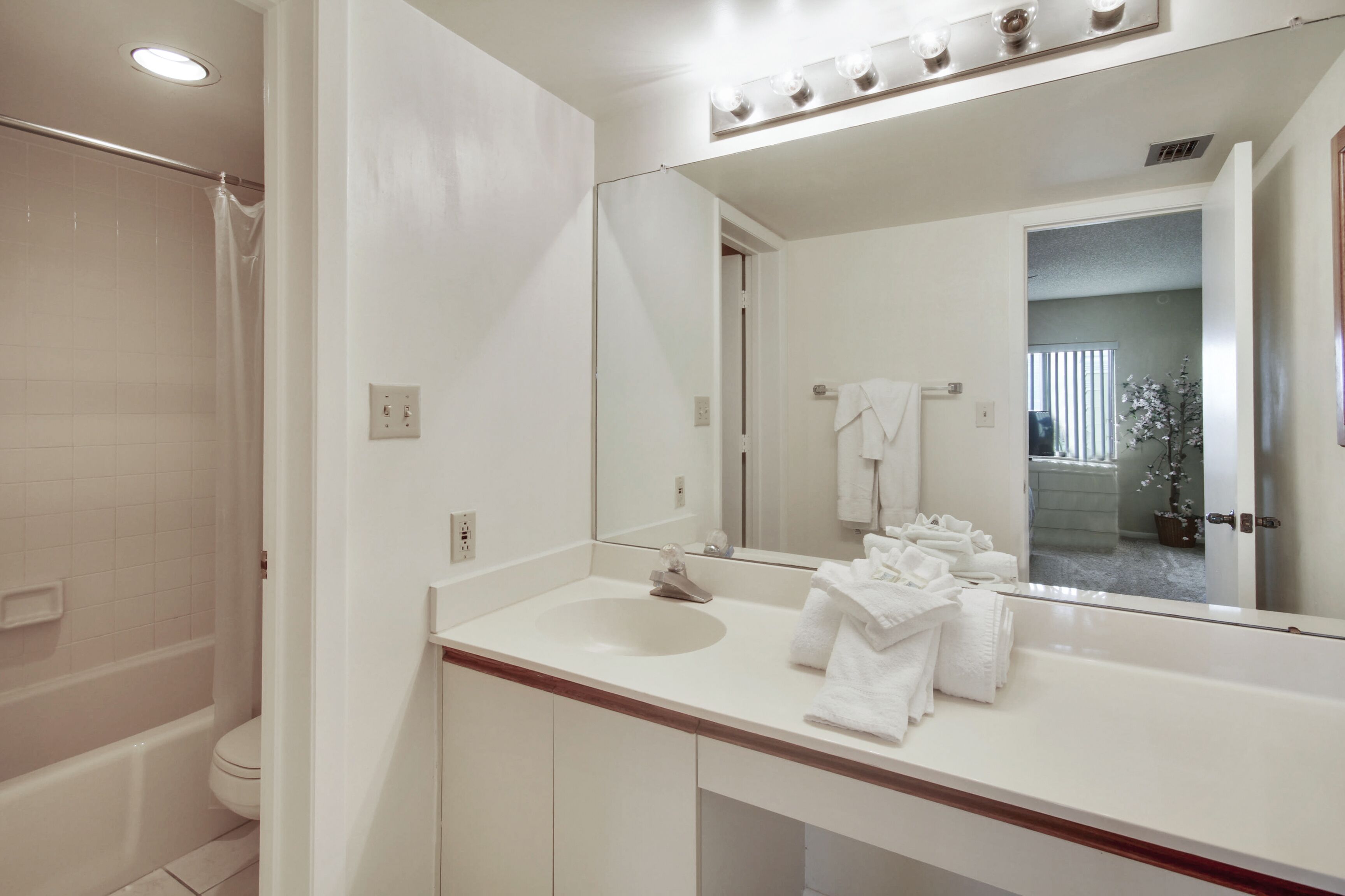 A bathroom with a white sink, a large mirror, and a shower.